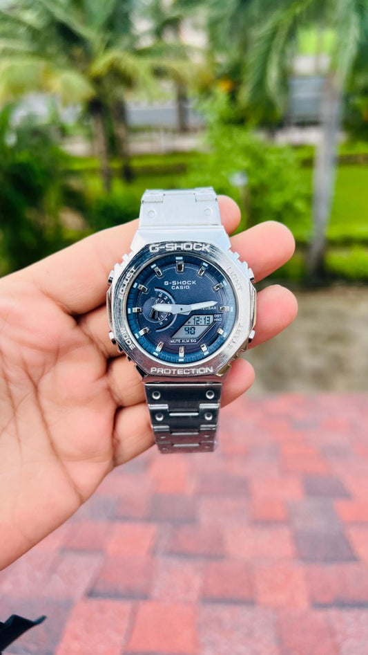 Hand holding a Casio G-Shock watch with a blurred outdoor background