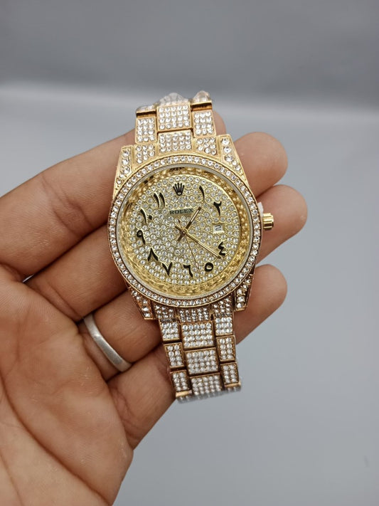 Gold watch with diamond accents held in a hand against a gray background
