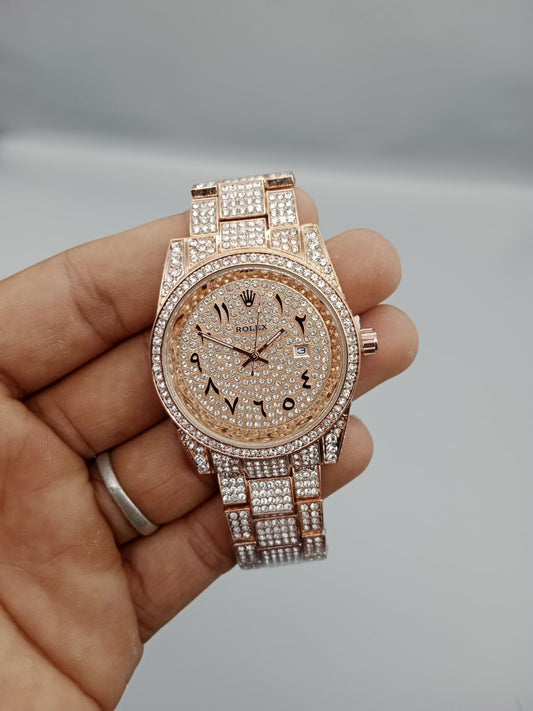Rose gold watch with diamond accents held in a hand against a neutral background