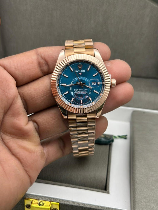 Gold watch with blue dial held in a hand, with a blurred background
