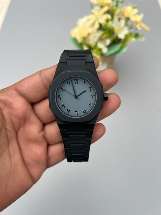 Black watch held in a hand with a blurred background