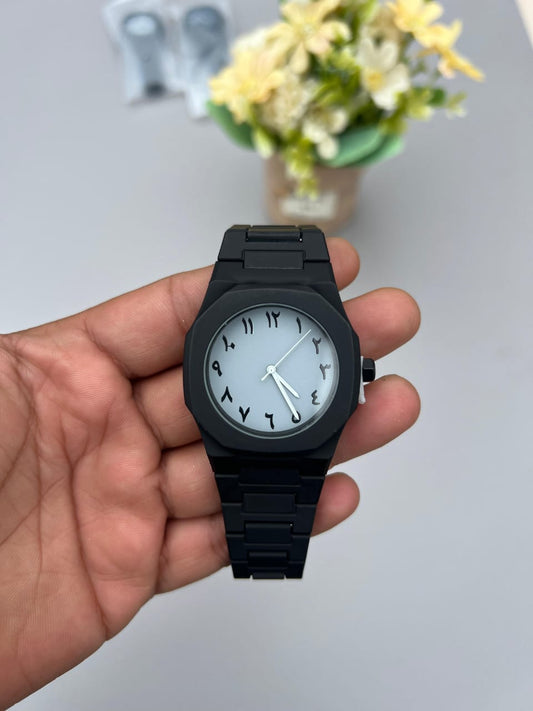 Black watch with white face held in a hand against a neutral background