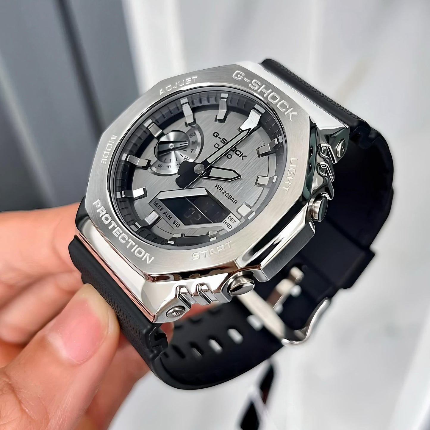 G-Shock watch with black strap held by a hand against a light background