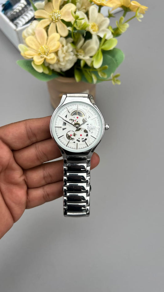 Silver watch held by a hand with a blurred background of flowers