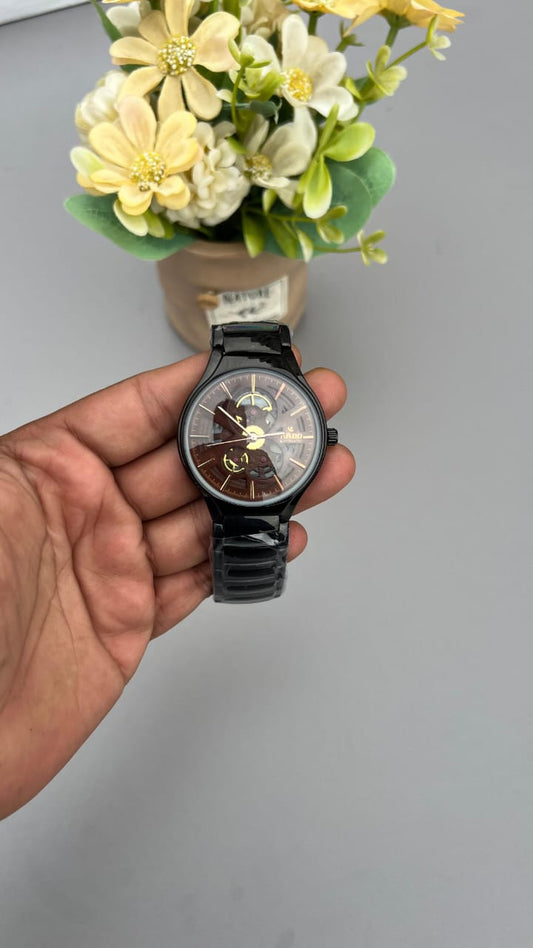Hand holding a black wristwatch with a blurred background of flowers