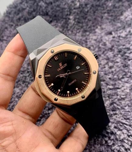Hublot watch held in a hand with a gray textured background